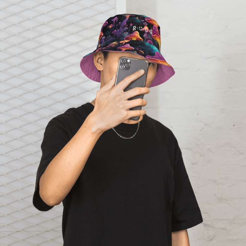 Unisex Reversible allover print bucket hat. Light purple on one side, with multicoloured mushroom pattern on the reverse. Available in 3 sizes: XS, S/M, and L/X