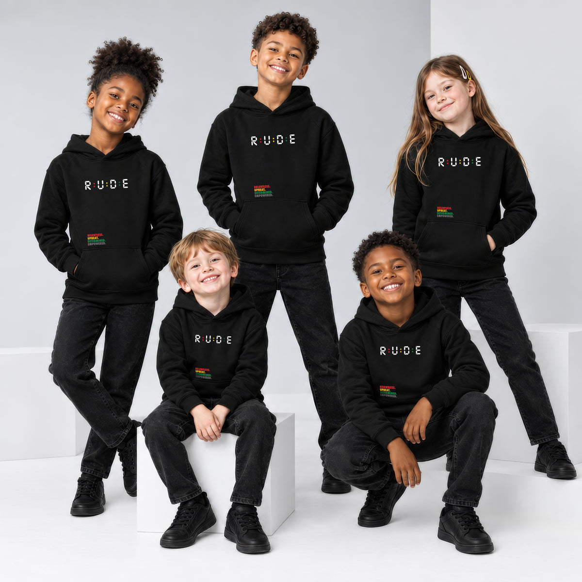 Five children modeling black Rude kids’ eco hoodies in a studio