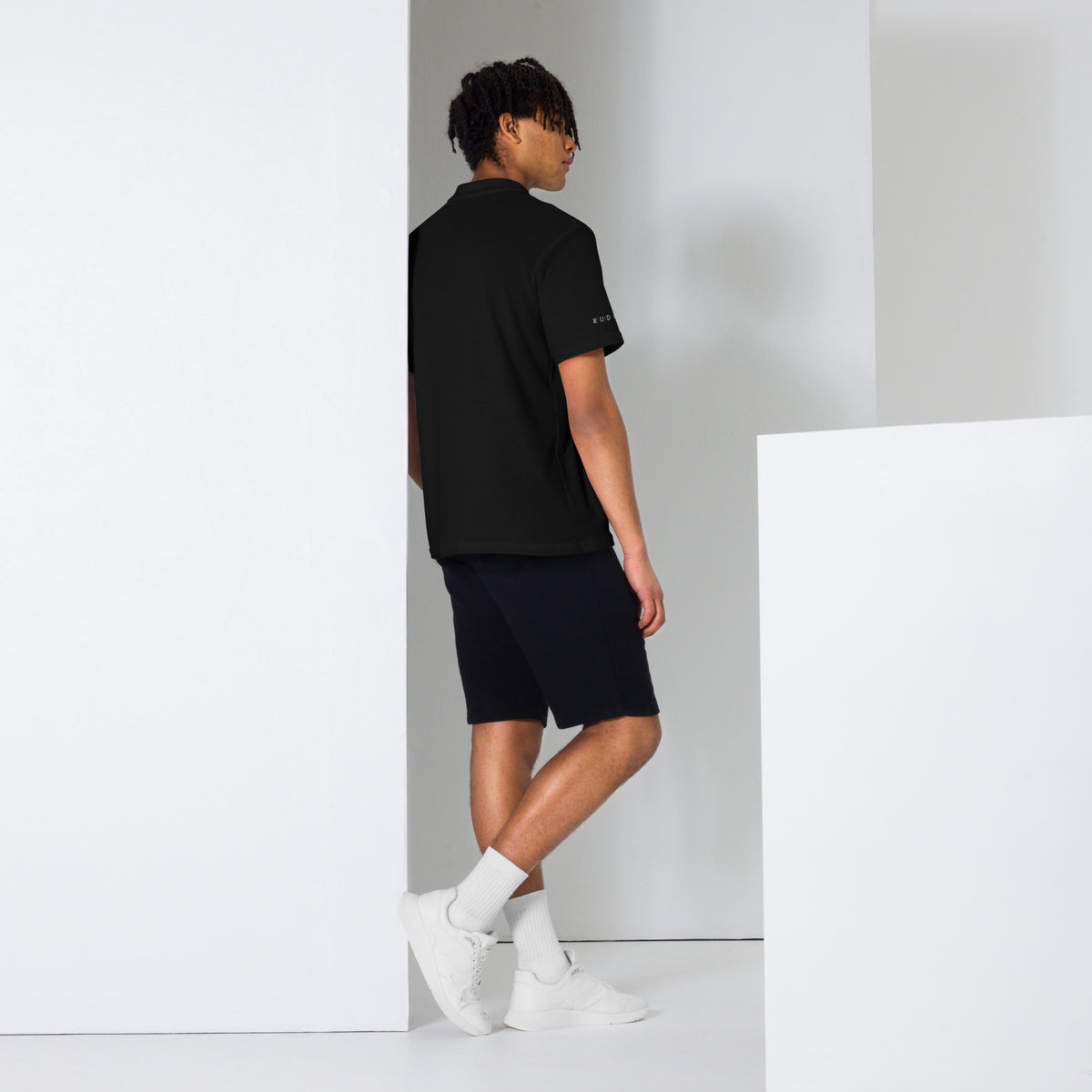 Back view of black unisex pique polo shirt showing the fit and collar