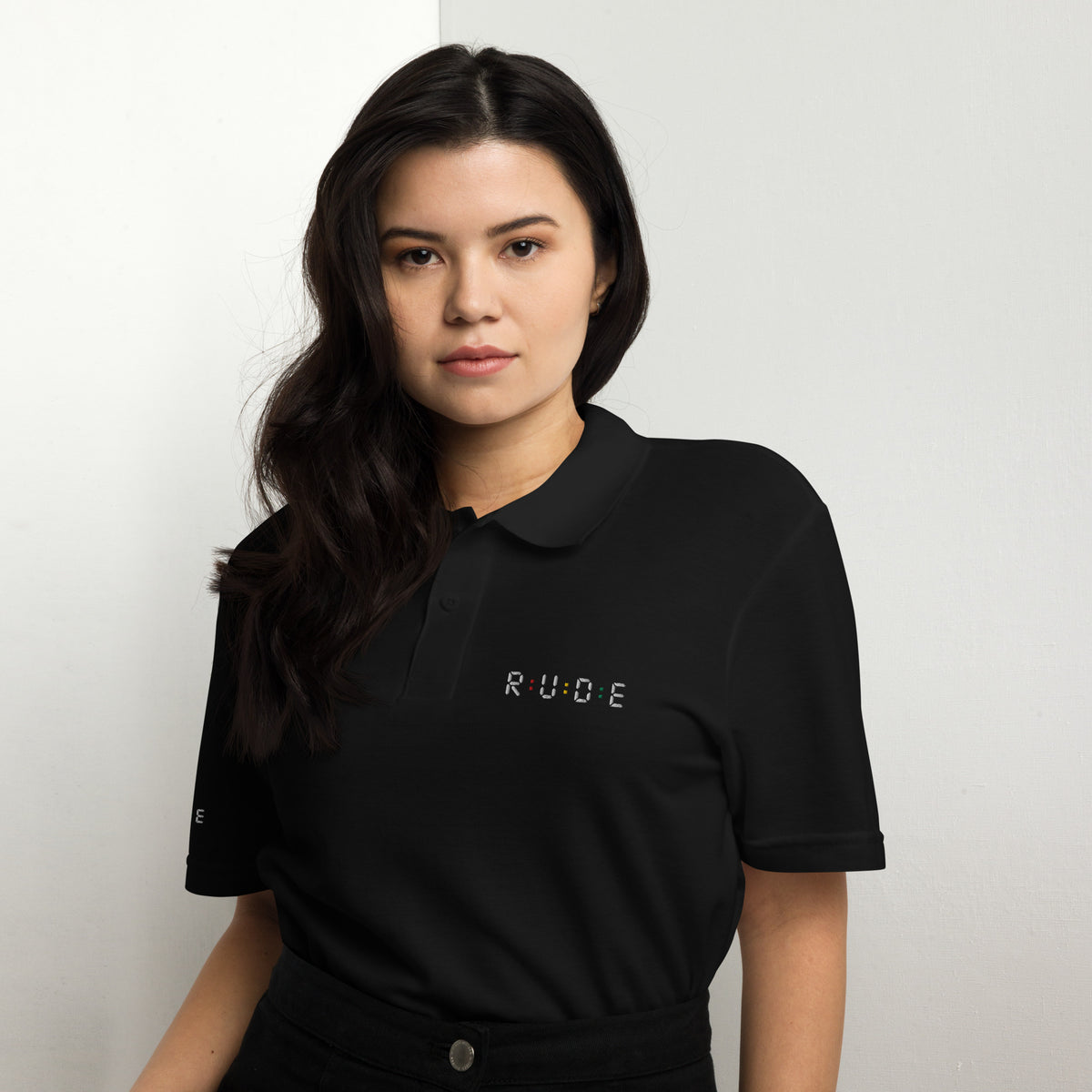 Black unisex pique polo shirt front view showing the collar and embroidered Rude logo