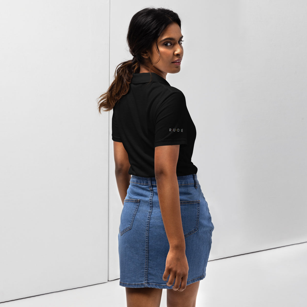 Back view of black women’s pique polo shirt with red, gold and green sleeve details.